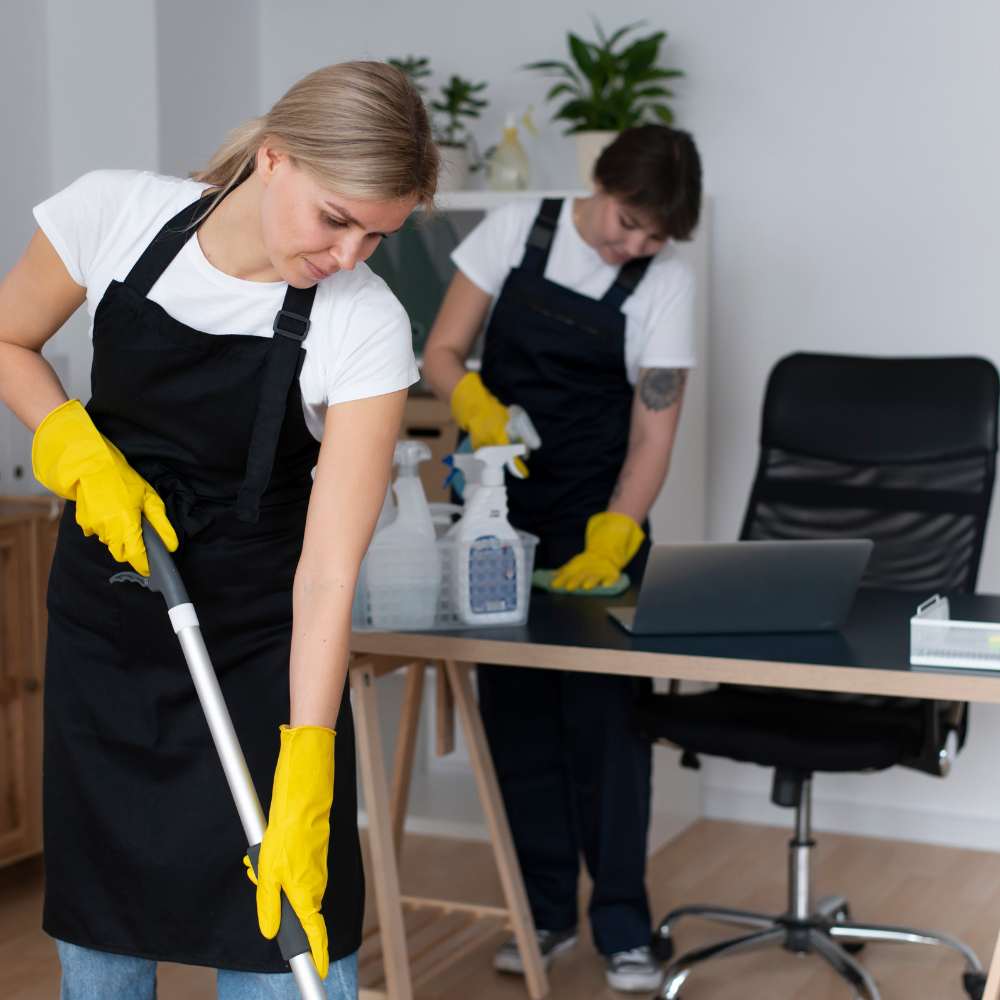 Woman cleaning an office working area with cleaning supplies.